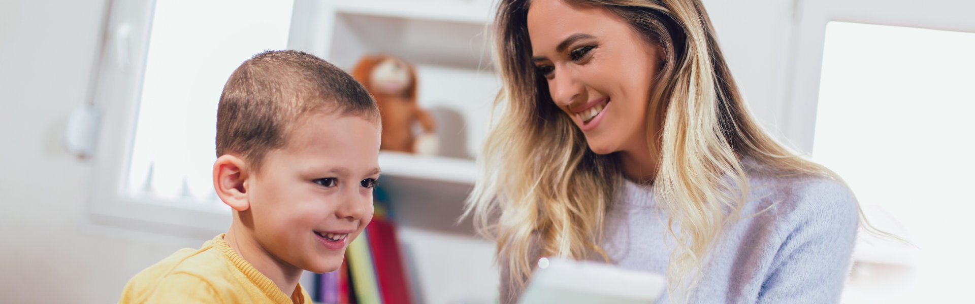 Young mother and her son play in kids room