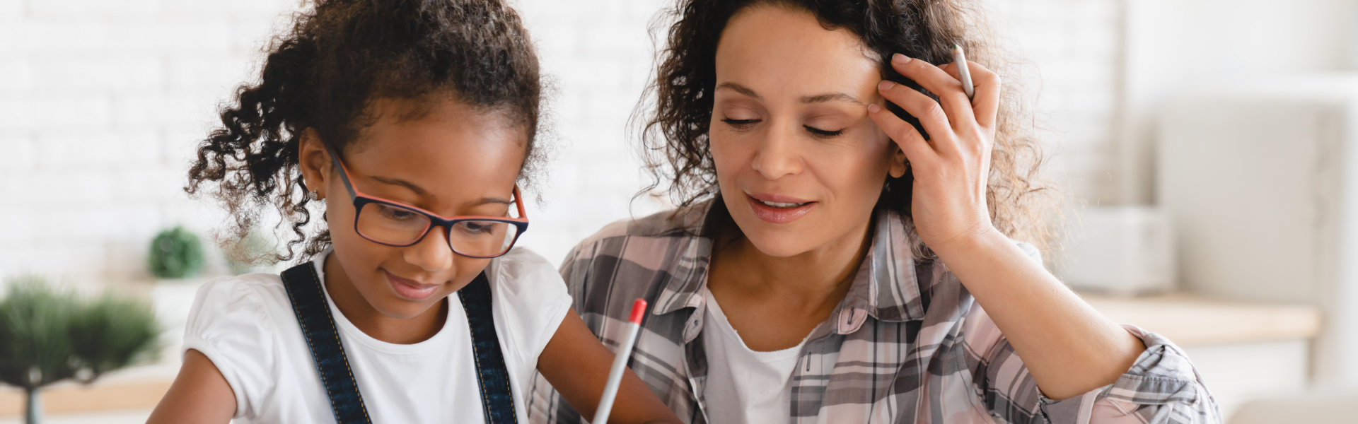 African-american mom mother tutor nanny childminder helping assisting with homework school project to a preteen daughter.